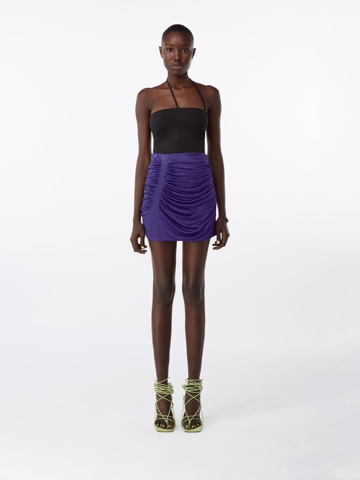 model wearing a purple draped skirt and a black shifted halter bodysuit