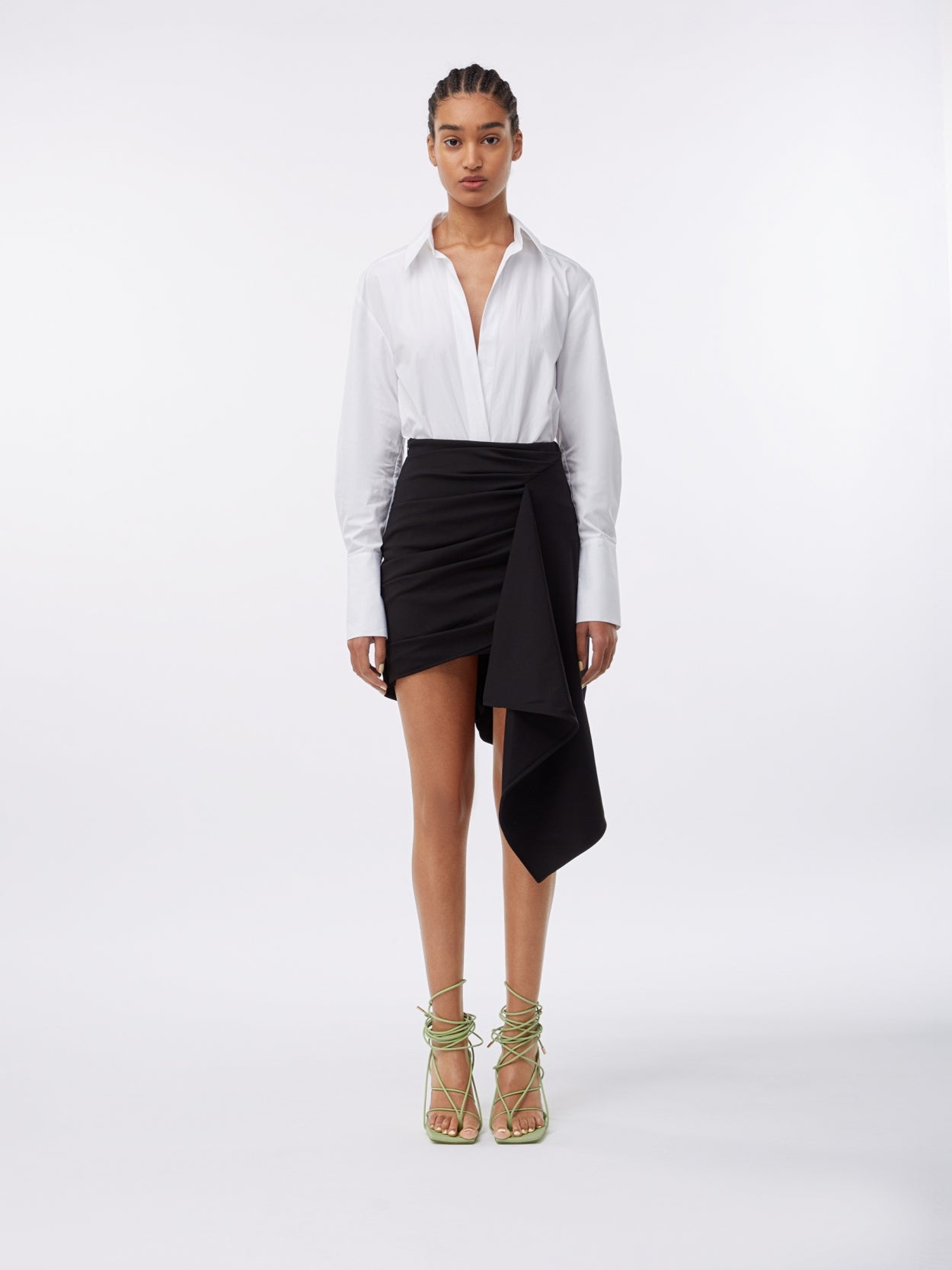 model wearing a black jersey draped skirt and a white shirt bodysuit